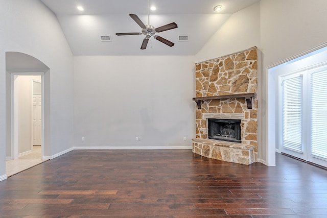 unfurnished living room featuring dark hardwood / wood-style floors, ceiling fan, a stone fireplace, and high vaulted ceiling