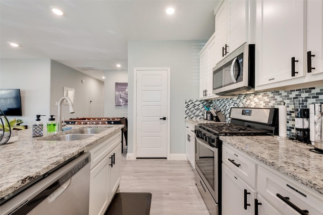 kitchen featuring white cabinetry, sink, stainless steel appliances, light stone counters, and light hardwood / wood-style flooring