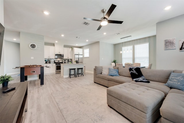 living room with ceiling fan, a healthy amount of sunlight, and light wood-type flooring