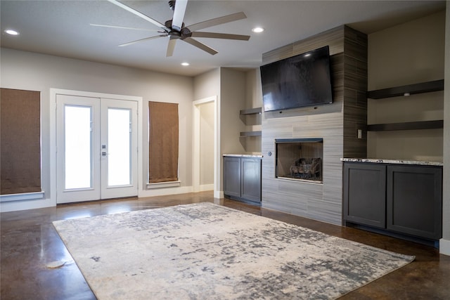 unfurnished living room featuring a tile fireplace, french doors, and ceiling fan