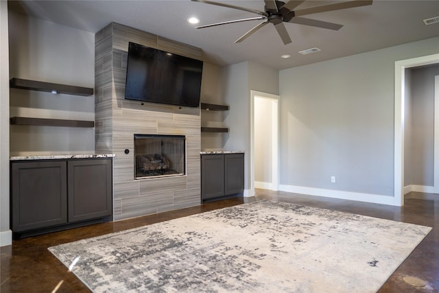 unfurnished living room featuring ceiling fan and a tiled fireplace