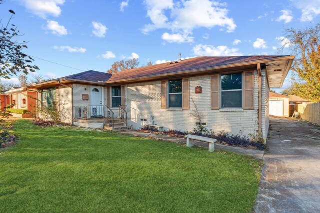 ranch-style home featuring a garage, an outdoor structure, and a front lawn