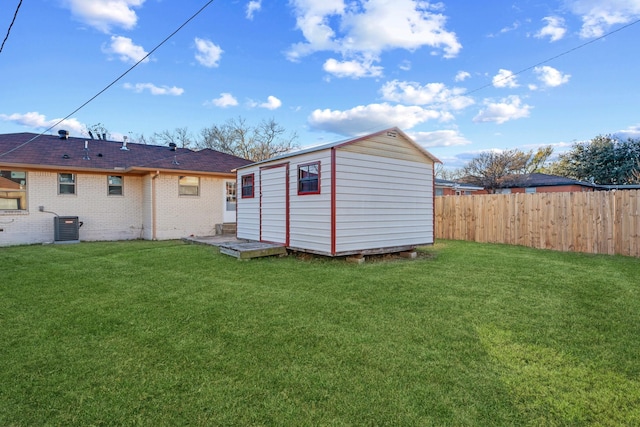 rear view of property with a storage shed, central AC unit, and a lawn