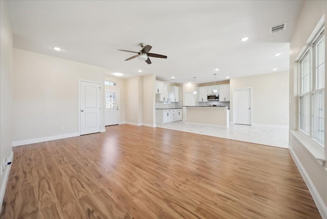 unfurnished living room featuring ceiling fan and light hardwood / wood-style flooring