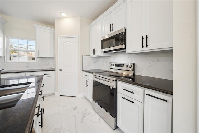 kitchen featuring white cabinets, appliances with stainless steel finishes, tasteful backsplash, and dark stone counters