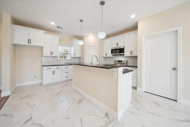 kitchen featuring a kitchen island with sink, white cabinets, hanging light fixtures, tasteful backsplash, and stainless steel appliances