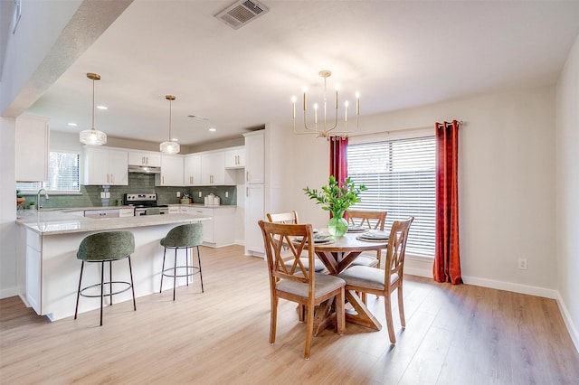 dining space with plenty of natural light, sink, a notable chandelier, and light wood-type flooring