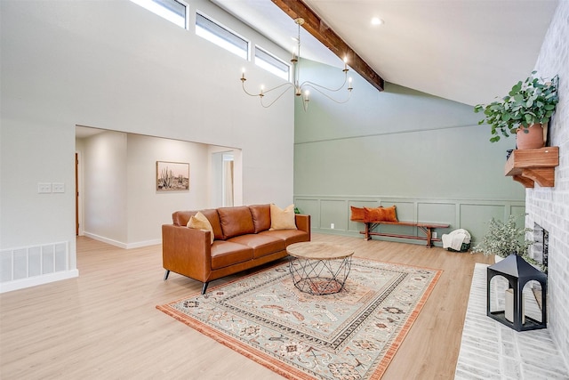 living room with hardwood / wood-style floors, high vaulted ceiling, a brick fireplace, beam ceiling, and a chandelier