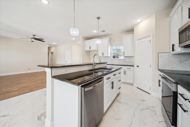 kitchen with white cabinetry, a kitchen island with sink, stainless steel appliances, and decorative light fixtures