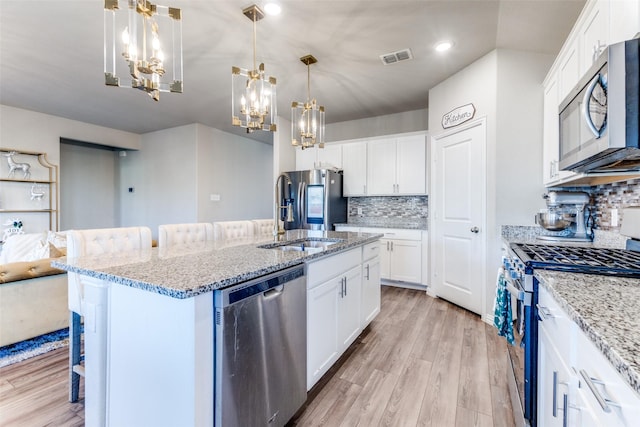 kitchen with appliances with stainless steel finishes, white cabinets, and a kitchen bar