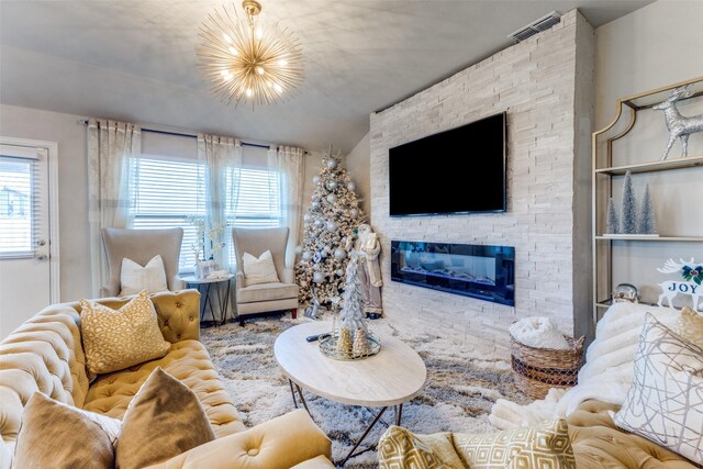 living room featuring a stone fireplace and an inviting chandelier