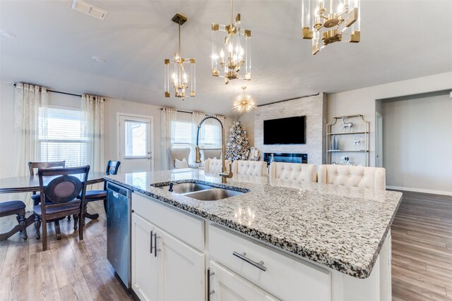 kitchen with sink, stainless steel dishwasher, pendant lighting, a center island with sink, and white cabinets