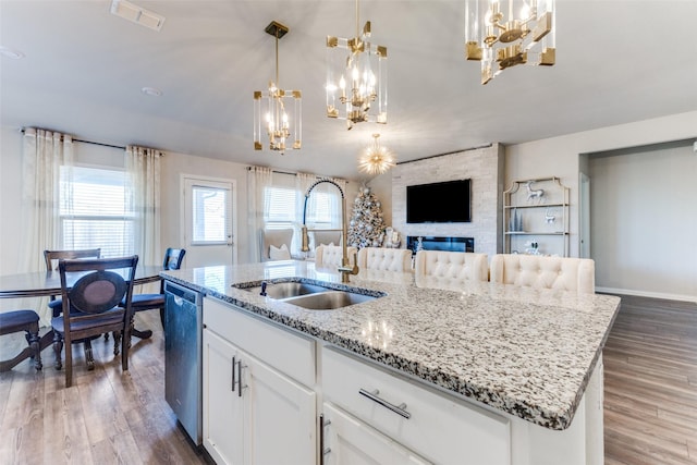 kitchen featuring sink, decorative light fixtures, stainless steel dishwasher, an island with sink, and white cabinets