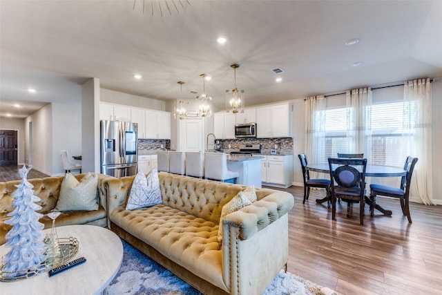 living room featuring a chandelier, light wood-type flooring, and sink