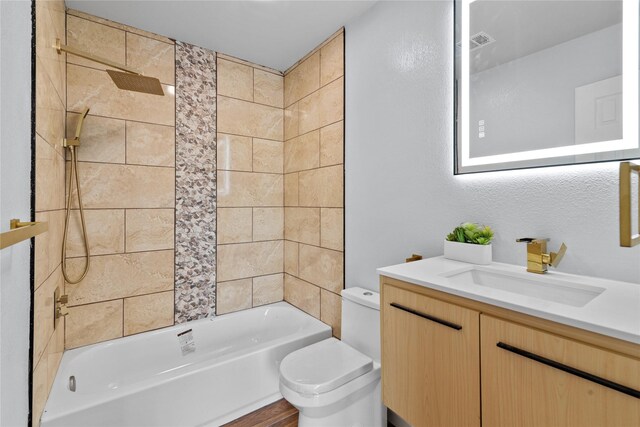 full bathroom with tiled shower / bath, vanity, and toilet