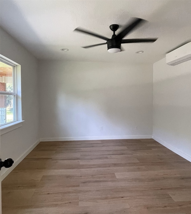 empty room featuring hardwood / wood-style flooring, a wall mounted AC, and ceiling fan