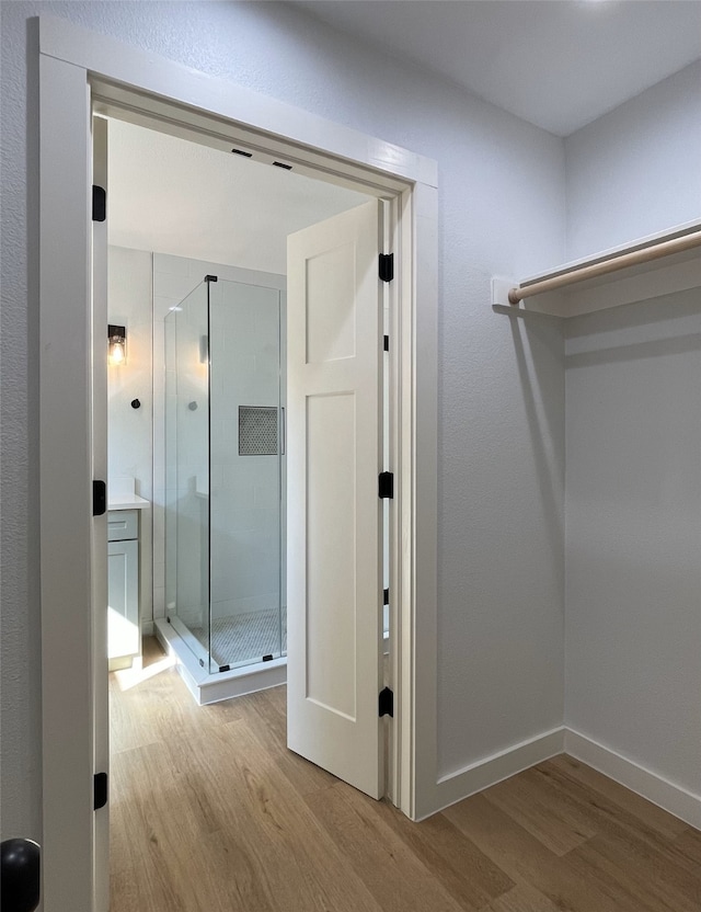 bathroom with wood-type flooring and a shower with shower door