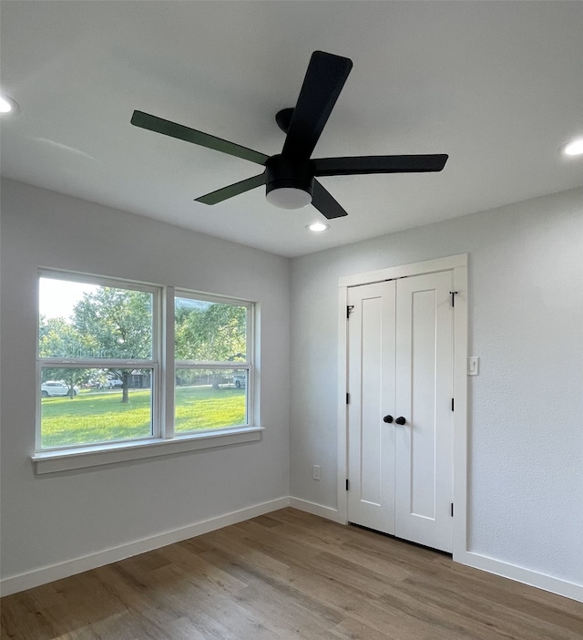 unfurnished bedroom featuring ceiling fan, a closet, and light hardwood / wood-style flooring