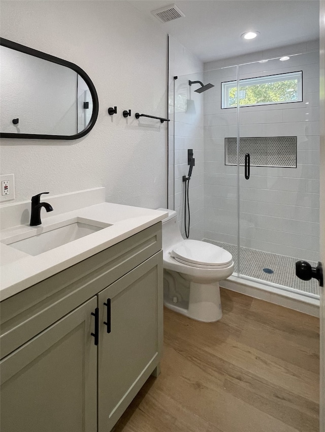 bathroom featuring vanity, an enclosed shower, hardwood / wood-style flooring, and toilet