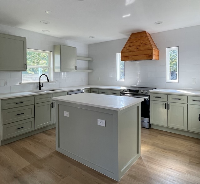 kitchen featuring sink, a kitchen island, custom range hood, electric stove, and light hardwood / wood-style floors