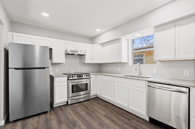 kitchen with light stone countertops, white cabinetry, sink, stainless steel appliances, and dark hardwood / wood-style floors