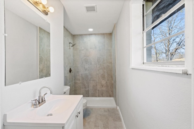 bathroom featuring a tile shower, vanity, toilet, and tile patterned floors