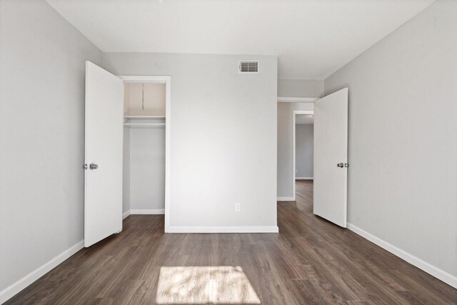 unfurnished bedroom with a closet and dark wood-type flooring