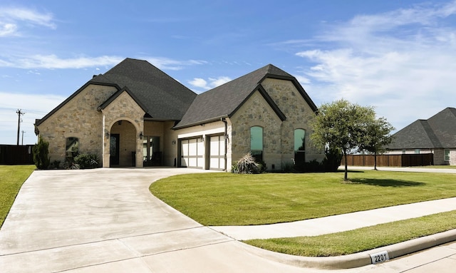 french country style house featuring a front lawn and a garage