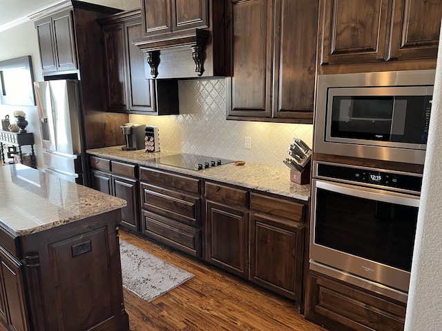 kitchen featuring dark wood-type flooring, stainless steel appliances, light stone counters, backsplash, and dark brown cabinets