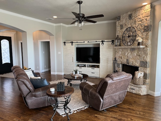 living room featuring ornamental molding, a textured ceiling, ceiling fan, a fireplace, and dark hardwood / wood-style floors