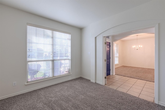 empty room with a notable chandelier and light colored carpet