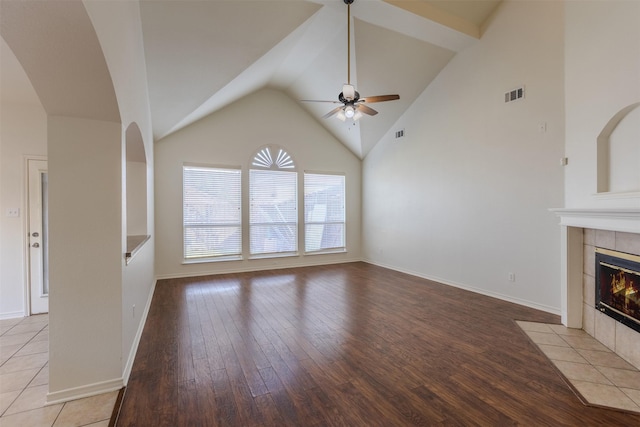 unfurnished living room with ceiling fan, light hardwood / wood-style floors, lofted ceiling, and a tiled fireplace