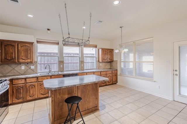 kitchen with decorative backsplash, appliances with stainless steel finishes, a kitchen island, and sink