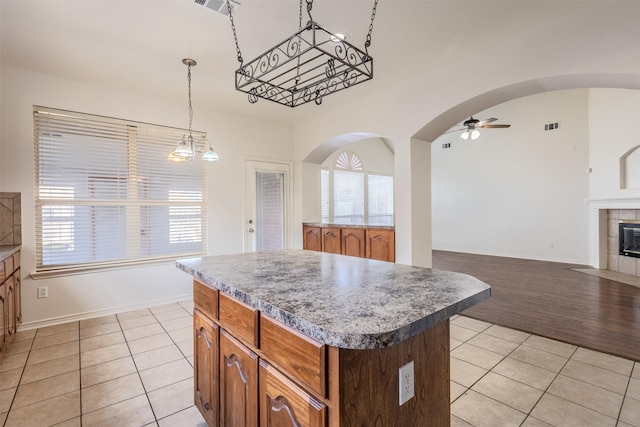 kitchen with ceiling fan with notable chandelier, light tile patterned floors, a center island, and decorative light fixtures