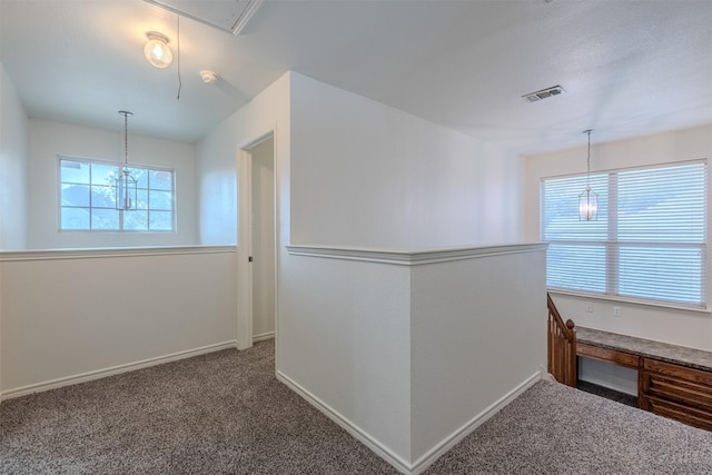 hall with carpet and an inviting chandelier