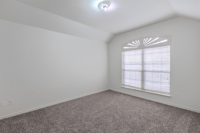 empty room featuring carpet flooring and vaulted ceiling