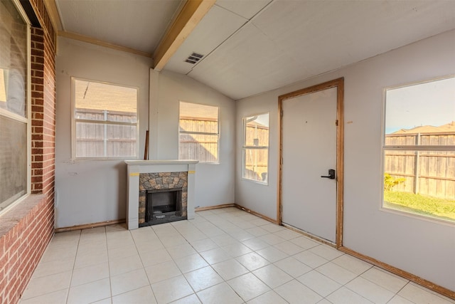 unfurnished living room featuring light tile patterned floors, a fireplace, a wealth of natural light, and vaulted ceiling