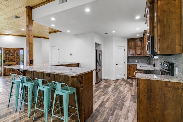 kitchen featuring decorative backsplash, light stone counters, stainless steel appliances, and dark wood-type flooring