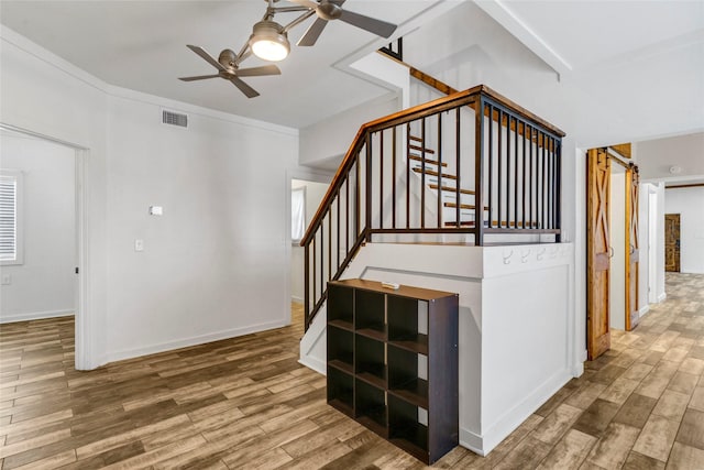 staircase with wood-type flooring, ceiling fan, and ornamental molding