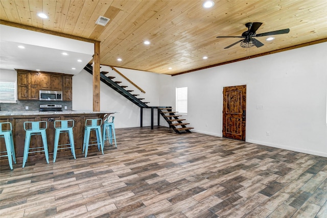 kitchen with a breakfast bar, stainless steel appliances, light stone countertops, and wooden ceiling