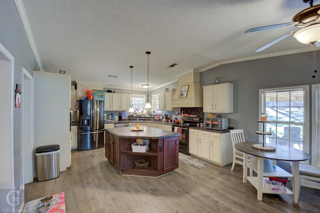 kitchen featuring stainless steel appliances, tasteful backsplash, lofted ceiling, a kitchen island, and custom range hood