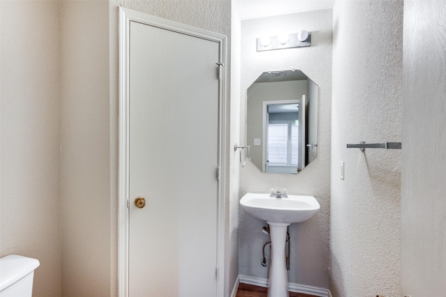 bathroom with a textured wall and toilet