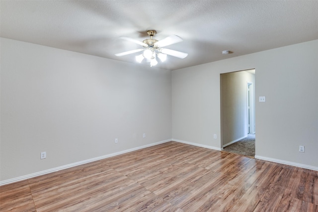 spare room with baseboards, ceiling fan, a textured ceiling, and light wood finished floors