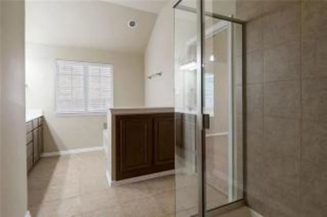 bathroom with walk in shower, tile patterned floors, lofted ceiling, and vanity