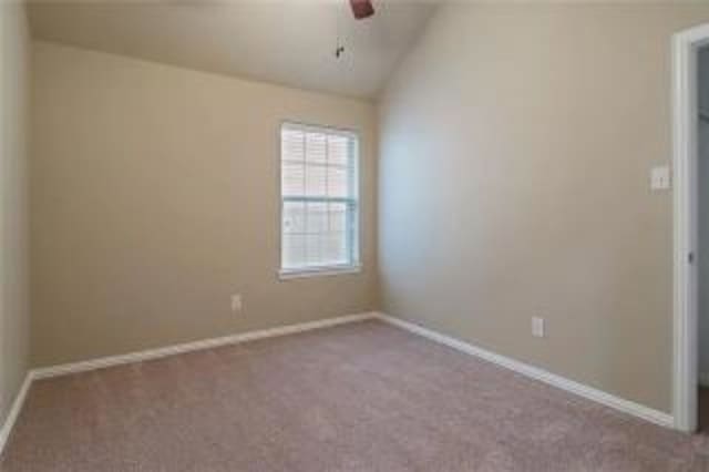 spare room featuring lofted ceiling, light colored carpet, and ceiling fan