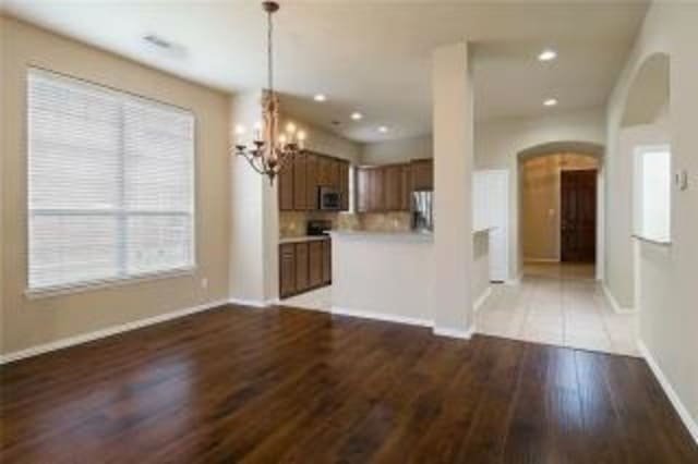 kitchen featuring pendant lighting, hardwood / wood-style flooring, appliances with stainless steel finishes, and an inviting chandelier