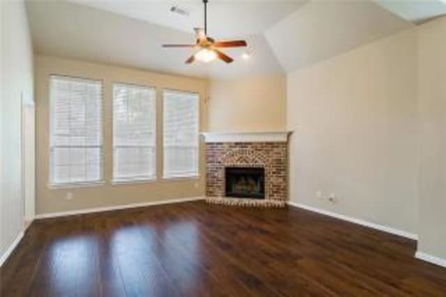 unfurnished living room with dark hardwood / wood-style flooring, a fireplace, ceiling fan, and vaulted ceiling