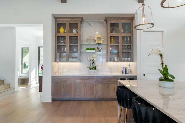 bar with decorative light fixtures, decorative backsplash, stairway, and light wood-type flooring