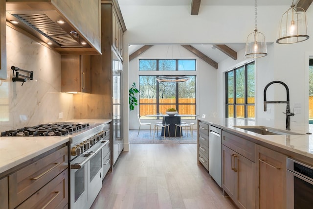 kitchen with sink, decorative light fixtures, lofted ceiling with beams, range with two ovens, and wall chimney range hood