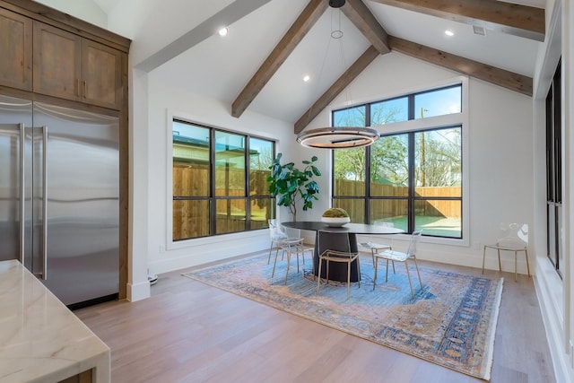 unfurnished dining area featuring a wealth of natural light, beamed ceiling, high vaulted ceiling, and light wood-style floors